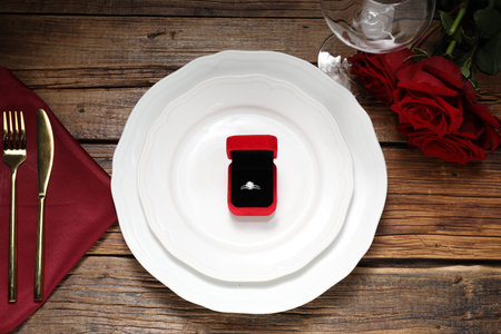 Beautiful table setting for romantic dinner, box with engagement ring and roses on wooden...