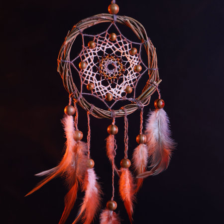 Beautiful dream catcher hanging in color lights on dark backgroundの写真素材