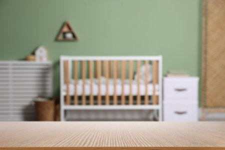 Empty wooden table against crib in baby room. Space for designの写真素材