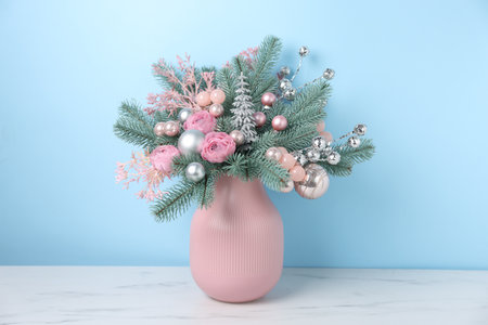 Beautiful composition with fir tree branches in vase on white marble table near light blue wall indoors. Winter decorの写真素材