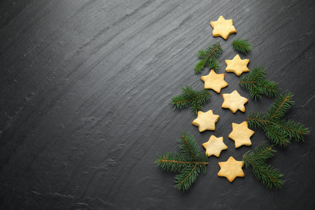 Christmas tree shape made of cookies and fir branches on black table, flat lay. Space for textの写真素材