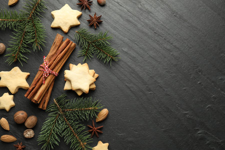 Christmas composition with fir tree branches, cookies and spices on black table, flat lay. Space for textの写真素材