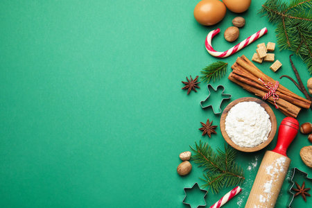Christmas composition with cookie cutters, fir tree branches and spices on green background, flat lay. Space for textの写真素材
