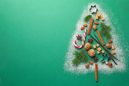 Christmas tree shape made with cookies, spices and fir branches on green background, flat lay. Space...