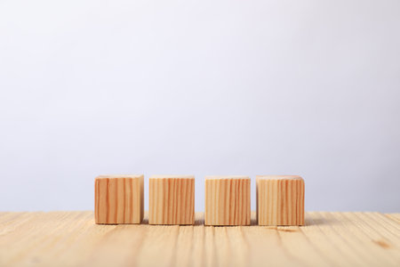 Blank cubes on wooden table against light background, space for text