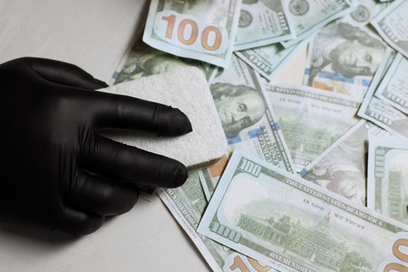 Man washing dollar banknotes with sponge at light gray table, closeupの写真素材
