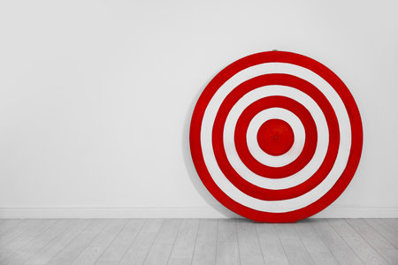 Round shooting target on floor near white wall, space for textの写真素材