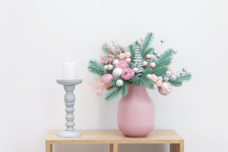 Beautiful composition with fir tree branches in vase and candle on wooden table near white wall. Winter decorの写真素材