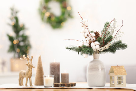 Beautiful composition with fir tree branches in vase and winter decor on wooden table against blurred lights, space for text. Bokeh effectの写真素材