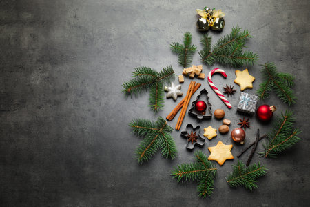 Christmas composition with fir tree branches, cookie cutters and spices on gray table, flat lay. Space for textの写真素材