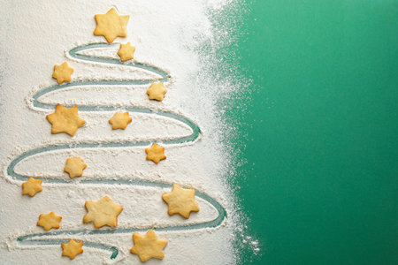 Christmas tree shape made with flour and cookies on green background, flat lay. Space for textの写真素材