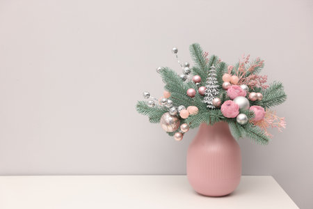 Beautiful composition with fir tree branches in vase on white table near light wall indoors, space for text. Winter decorの写真素材