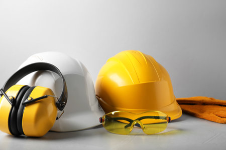 Hardhats, protective goggles, gloves and earmuffs on light background. Safety equipmentの写真素材