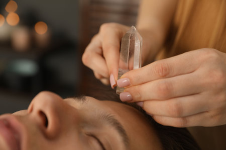 Man undergoing crystal therapy to heal or restore his aura indoors, closeupの写真素材