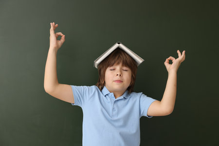 Back to school. Boy with book against chalkboard indoorsの写真素材