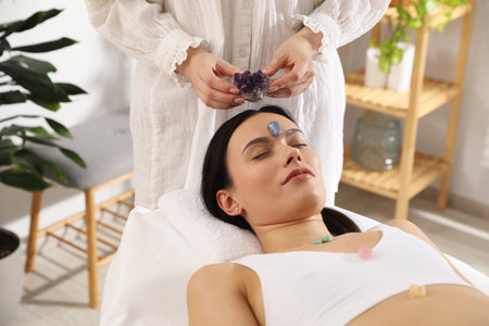 Woman undergoing crystal therapy to heal or restore her aura indoorsの写真素材