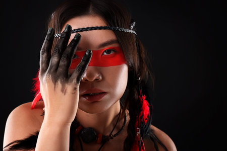 Shaman woman with face painting on black background, space for text