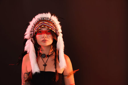 Shaman woman in native American Indian headdress with face painting on dark background, space for...