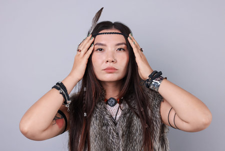 Shaman woman in feather headdress on light gray background
