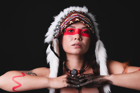 Shaman woman in native American Indian headdress with face painting on black background