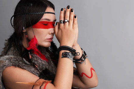 Shaman woman with face painting on light gray background, space for text