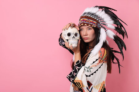 Shaman woman in native American Indian headdress with skull on pink background, space for text