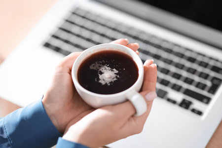 Woman having coffee break near laptop, closeupの写真素材