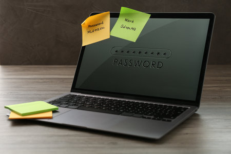 Laptop with password and paper notes on wooden tableの写真素材