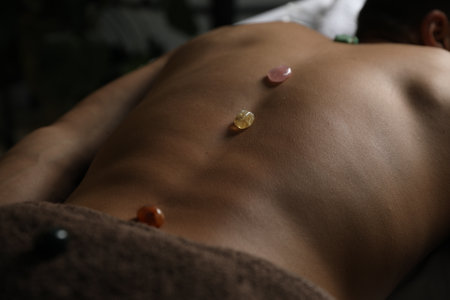 Man undergoing crystal therapy to heal or restore his aura indoors, closeupの写真素材
