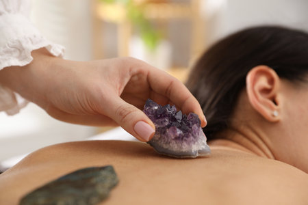 Woman undergoing crystal therapy to heal or restore her aura indoors, closeupの写真素材
