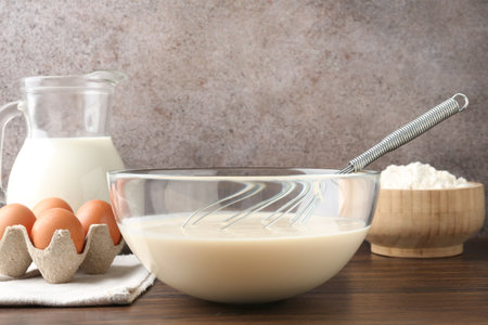 Liquid dough in bowl, ingredients on wooden table, closeupの写真素材
