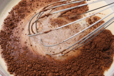 Adding cocoa powder into bowl with dough, closeupの写真素材