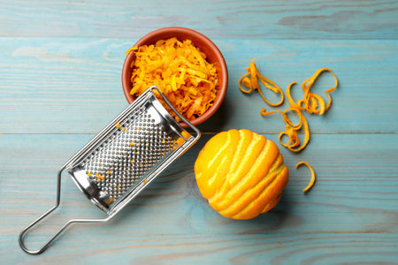 Orange zest, fresh fruit and grater on light blue wooden table, flat layの写真素材