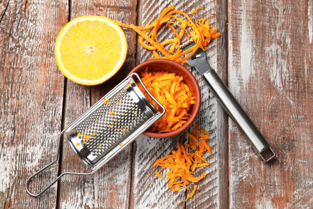 Orange zest, fresh fruit, zester tool and grater on wooden table, flat layの写真素材