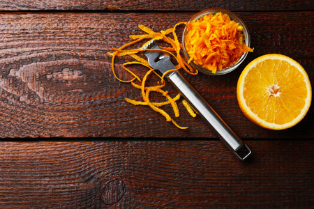 Orange zest, fresh fruit and zester tool on wooden table, flat lay. Space for textの写真素材