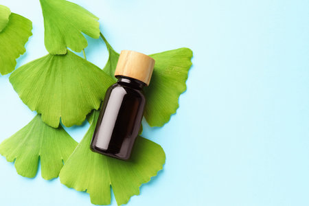 Ginkgo biloba leaves and essence on light blue background, flat lay. Space for textの写真素材