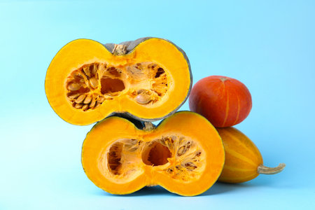 Whole and cut pumpkins on light blue background, closeup. Gourd familyの写真素材