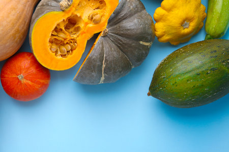 Many fresh pumpkins and other gourds on light blue background, flat lay. Space for textの写真素材