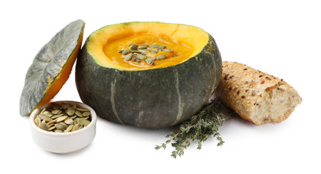 Tasty pumpkin cream soup with seeds, thyme and bread served in pumpkin isolated on whiteの写真素材