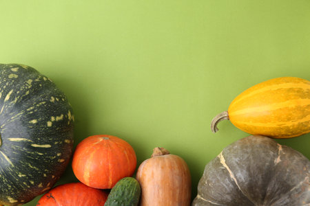 Many fresh pumpkins and cucumber on green background, flat lay with space for text. Gourd vegetablesの写真素材