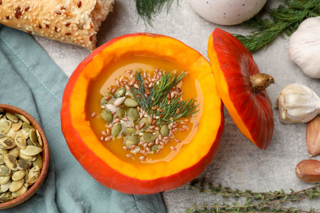 Tasty pumpkin cream soup with seeds, herbs, garlic and bread on gray textured table, flat layの写真素材