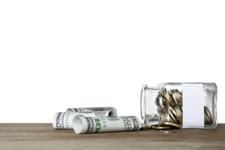 Overturned jar with blank note and money on wooden table against white background