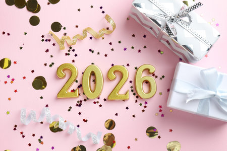 New 2026 Year. Golden numbers, confetti and gift boxes on pink background, flat lay