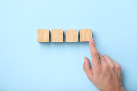 Man with wooden cubes on light blue background, top viewの写真素材