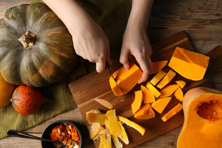 Woman cutting pumpkin at wooden table, top viewの写真素材