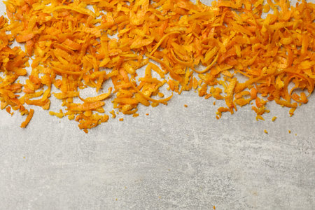 Fresh orange zest on light gray table, flat lay. Space for text