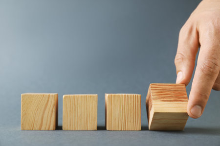 Man with wooden cubes on gray background, closeup. Space for textの写真素材