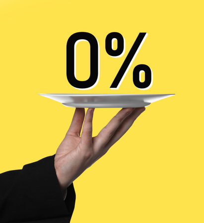 Waiter holding plate with 0 percent sign against yellow background, closeup. Zero commissionの写真素材