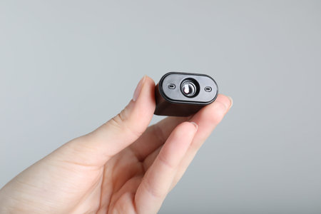 Woman with hidden spy camera on light gray background, closeup
