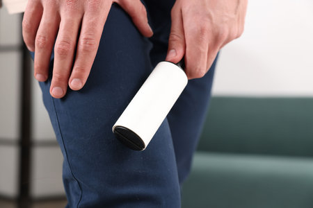 Man cleaning pants with lint roller at home, closeupの写真素材